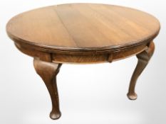 An Edwardian oak oval dining table on pad feet,