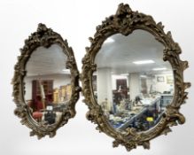 A pair of ornate gilt plaster reproduction oval mirrors, length 67cm.