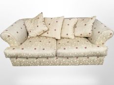 A contemporary three seater settee in gold floral upholstery,