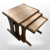 A G-plan nest of three teak tables with textured copper tops,