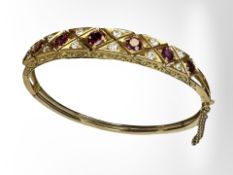 A yellow gold diamond and ruby bangle, internal dimensions approximately 56 mm x 50 mm, 16.1g.