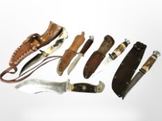 A group of five hunting knives, four of which in leather sheaths.
