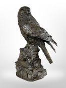 A contemporary hollow cast patinated bronze figure of a bird of prey perched on rock,
