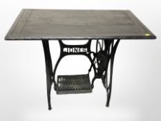 A Jones cast iron sewing machine treadle base with ebonised plank top, width 90cm.