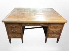 A 1920's panelled oak partner's desk, fitted seven drawers to each side with later plate glass top,