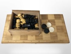 A wooden folding chessboard and a set of turned and stained boxwood pieces, quantity of checkers.