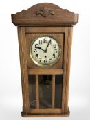 An early 20th century oak eight day wall clock with silver dial, length 79cm.