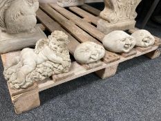 A concrete garden cherub figure and three further happy face stones.