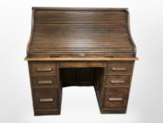 A 1920's oak tambour front twin pedestal writing desk with original key, 122cm x 77cm x 120cm.