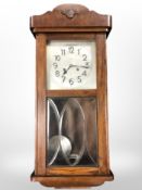 A continental oak eight day wall clock with silvered dial and pendulum,