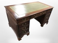A reproduction mahogany nine drawer twin pedestal writing desk, 130cm x 76cm x 75cm.