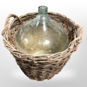 A wicker hamper, containing a large glass carboy, height 58cm.