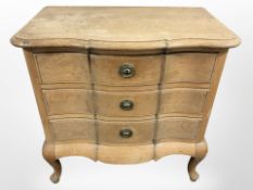 An early 20th century continental blond oak serpentine front three drawer chest, 66cm x 40cm x 65cm.