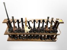 A wooden pipe rack containing 24 various pipes including Meerschaum example with amber stem and