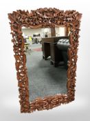 A contemporary eastern heavily carved hardwood mirror, length 98cm.