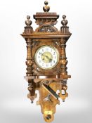 A carved beech eight day wall clock with pendulum and key,