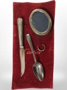 A small silver oval photograph frame, a teaspoon, a silver handled knife and a ring.
