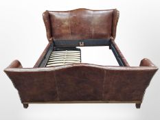 A contemporary stitched and studded chestnut brown leather 6' bed frame with base,