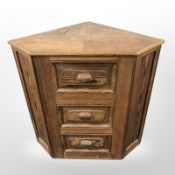 A pine three drawer corner cabinet,