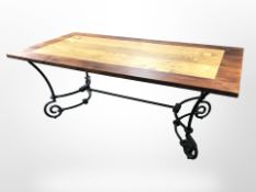 A contemporary stained pine dining table on wrought metal support,