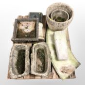 A pallet of several garden concrete planters, curved bench top,