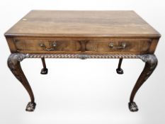 A carved walnut two drawer side table on claw and ball feet,