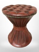 An hourglass shaped buttoned leather footstool, height 48cm.