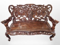 An oriental heavily carved hardwood three seater bench, with carved dragon arm rests,