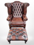 A Chesterfield oxblood buttoned leather wing back armchair and matching footstool