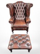 A Chesterfield oxblood buttoned leather wing back armchair and matching footstool