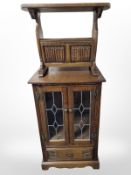 A modern carved oak linen fold magazine table, and a leaded glass door cabinet,