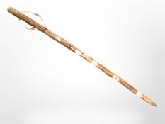 A rustic wooden walking stick inset various enamelled plaques,