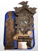 A carved reproduction cuckoo clock, carving of a Saint, pair of turned wooden candlesticks,