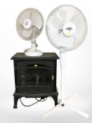 An electric heater in the form of a fire and two fans.
