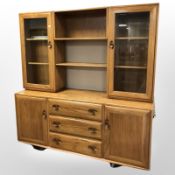 An Ercol elm display cabinet fitted with cupboards and drawers beneath, 155 cm x 44 cm x 162 cm.