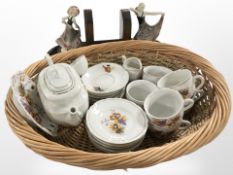An oval wicker basket, a pair of oak and ceramic figural bookends, and a floral-decorated tea set.