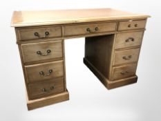 A reproduction oak nine drawer twin pedestal desk with leather inset panel, 120 cm x 69 cm x 77 cm.