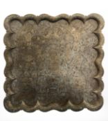 An Indian square scalloped edge brass tray depicting figures amongst foliage,