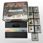 An Atari 7800 gaming console with nine various cassettes and original box.