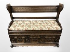 A reproduction carved oak storage hall settle, 117 cm x 43 cm x 97 cm.