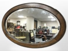 An Edwardian oak oval mirror, width 77 cm.