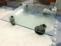A square glass low coffee table on trolley castors,