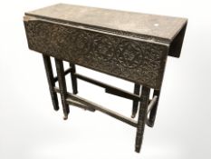 A Victorian heavily carved and ebonised drop leaf gate leg table,