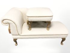 A contemporary chaise lounge on gilt legs, with matching stool.