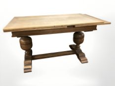 An early 20th century oak pull-out refectory dining table on turned bulbous supports,