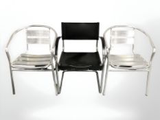A chrome and black vinyl armchair and two further aluminium chairs.