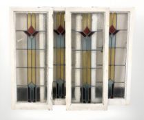 Four early 20th century stained and leaded glass windows in painted frames,
