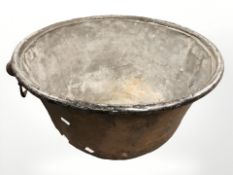 A 19th century patinated copper twin-handled pot with cast iron handles, diameter 55 cm.