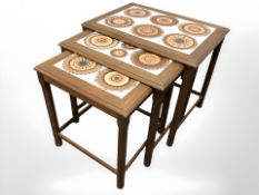 A Danish teak nest of three tile inset tables, width 55 cm.