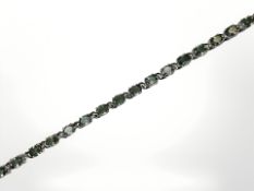 A 9ct white gold green garnet line bracelet, length 20cm. CONDITION REPORT: 8.